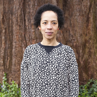 Woman looking into a camera in front of a tree