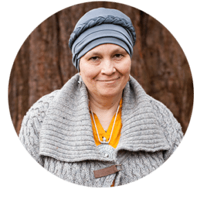 A smiling woman with grey headwear and a fluffy grey cardigan