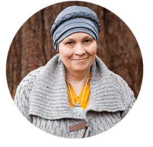 A smiling woman with grey headwear and a fluffy grey cardigan 