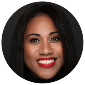 A black woman smiling into camera. She is wearing red lipstick and has dark hair